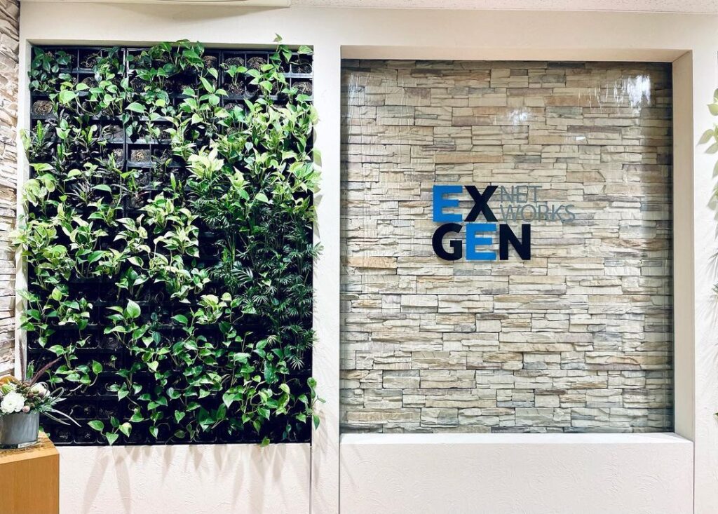 EXGEN NETWORKSのオフィスエントランスは、壁面の緑と石積み壁による洗練された空間です