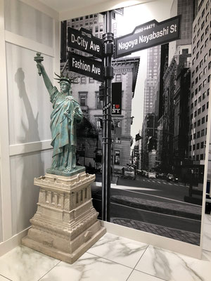 ニューヨークと名古屋を融合させた街角風景の壁紙と自由の女神像のミニチュアで装飾されたホテルの内装