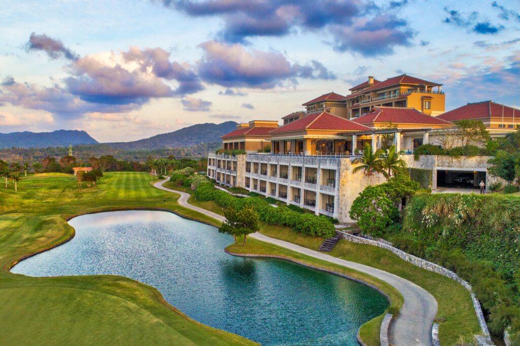 THE RITZ-CARLTON OKINAWAの空撮。特徴的な赤い屋根のホテルの前には、池のあるゴルフコースが広がっています