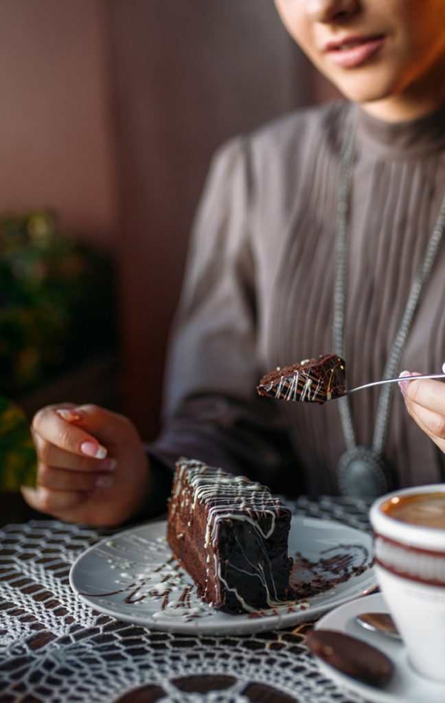女性がフォークでチョコレートケーキを食べようとしています